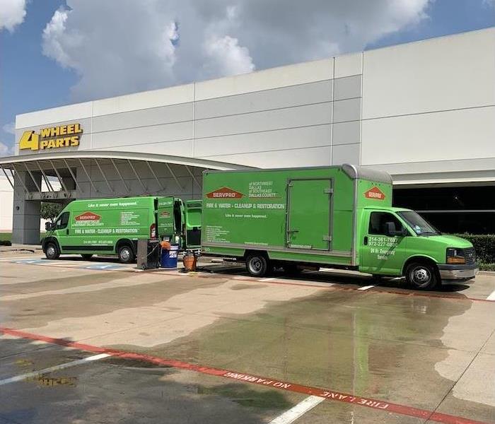 SERVPRO van and box truck in a parking lot in front of a cream building