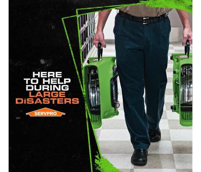 SERVPRO tech carrying air drying tool with the caption: HERE TO HELP DURING LARGE DISASTERS